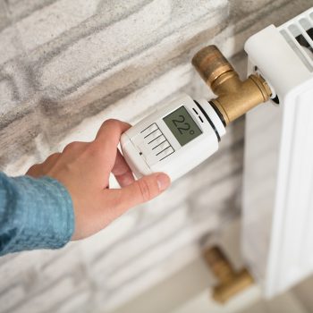 A Person's Hand Adjusting Temperature On Thermostat Of Radiator